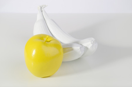 Yellow apple and two white bananas on white background.の写真素材