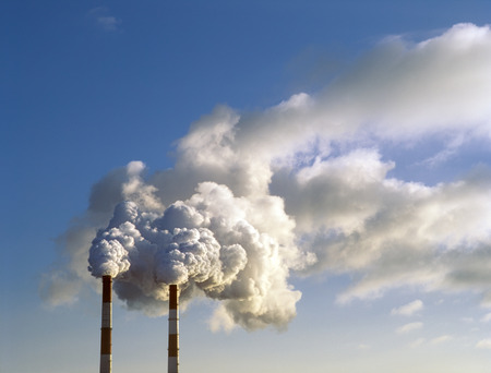 Air pollution by smoke coming out of two factory chimneys.の写真素材