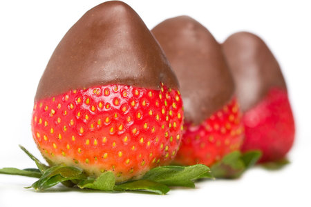 Three delicious chocolate covered strawberries with green leaves.の写真素材