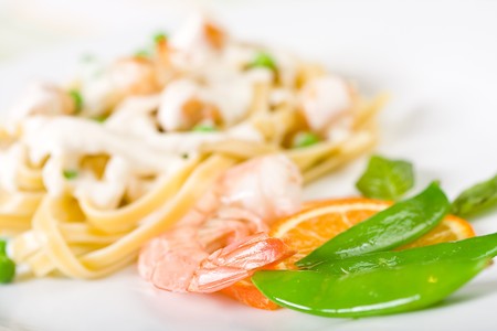 Scallops, Shrimp, and Pasta with Peas on a white plateの写真素材