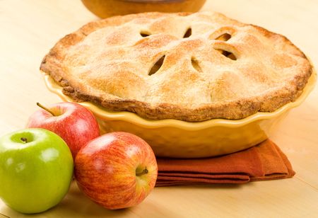 Whole apple pie in yellow baking dish on wood surfaceの写真素材