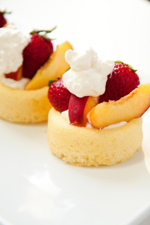 Simple summer fruit dessert peaches, strawberries, whipped cream and sponge cakeの写真素材