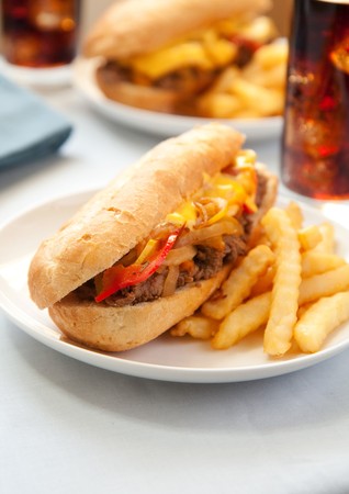 cheesesteak sandwich accompanied by fries and an ice cold colaの写真素材