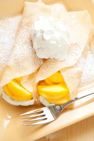 Peach crepes with a large dollop of whipped creamの写真素材