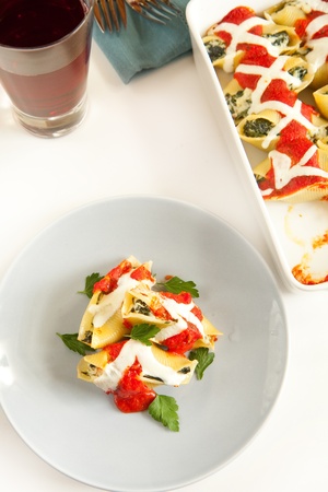 Stuffed pasta shells on blue plate with garnishの写真素材