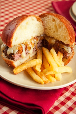 Thick rare cheeseburger with swiss cheese and caramelized onions served with french friesの写真素材