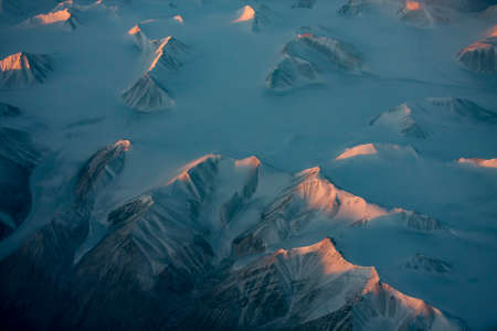 Aerial view of snowy mountain peaks of Greenland during sunsetの写真素材