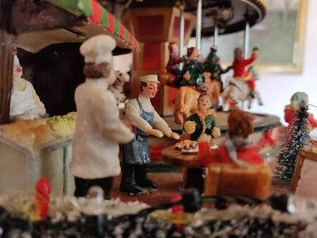A doll and miniature sculpture of a carnival scene with carousal in the background. The doll is serving the customersの写真素材