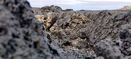 Macro shot of volcanic black rock and sky on the hyeopjae beach while in vacation in jeju island, south koreaの写真素材