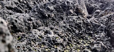 Macro shot of volcanic black rock on the hyeopjae beach while on vacation in jeju island, south koreaの写真素材