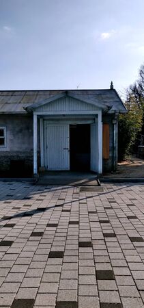 An abandoned old house with white wooden door and brick pavement with tin roof somewhere in Koreaの写真素材