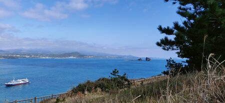 Landscape view of blue sea and sky with boat seen from songaksan mountain in Jeju Island, South Koreaの写真素材
