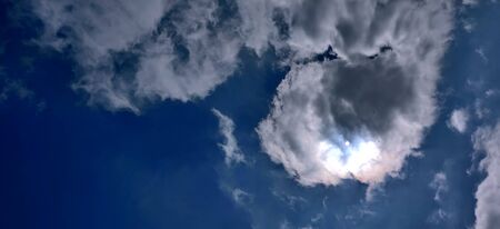 Sun breaking out from behind winter clouds in blue sky in Jeju Island, South Koreaの写真素材