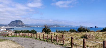A paved foot path in songaksan mountain with sanbang-san mountain in background in Jeju Island, South Koreaの写真素材