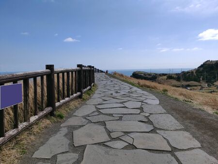 A paved foot path for hikers and walkers in songaksan mountain on the shores of ocean in Jeju Island, South Koreaの写真素材