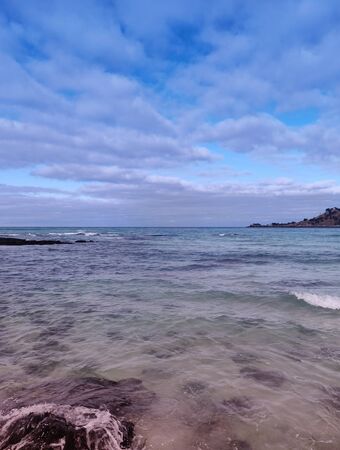 Various hues of a vertical landscape of sea and cloudy sky on Hyeopjae beach with volcanic rocks in Jeju Island, South Koreaの写真素材