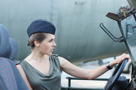 Young attractive female soldier driving the carの写真素材