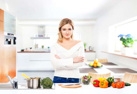 Young and beautiful housewife woman cooking in a kitchenの写真素材
