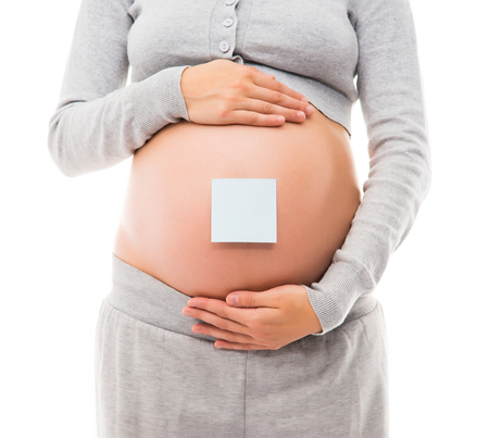 Belly of a young pregnant woman in sporty clothes. A white sticker is on the belly. Image isolated on a white background.の写真素材