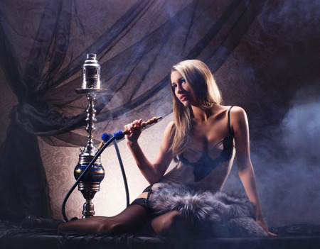Young sexy woman in luxury underwear smoking the hookah in vintage interiorの写真素材