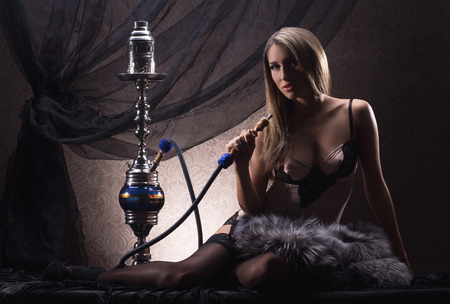 Young sexy woman in luxury underwear smoking the hookah in vintage interiorの写真素材