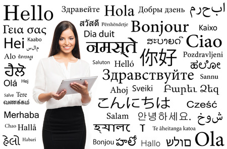 Young attractive woman with and ipad over the background with a different world languages (language school concept)の写真素材