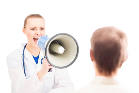 A young and attractive female doctor with a megaphone yelling on a patient. Image isolated on a white background.の写真素材