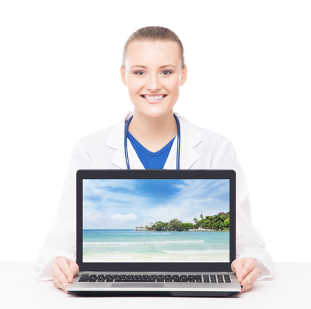 Young, professional and cheerful female doctor showing resort photo on a laptopの写真素材
