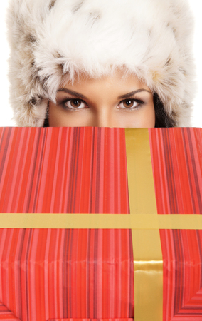 Young and beautiful woman holding a nice Christmas present over white backgroundの写真素材