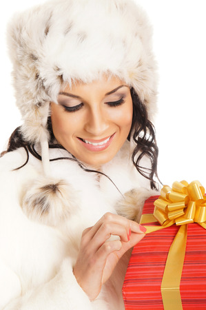 Young and beautiful woman holding a nice Christmas present over white backgroundの写真素材