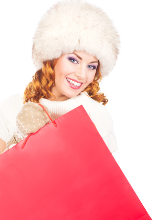 Young and beautiful shopper in winter dress with the bags isolated on whiteの写真素材