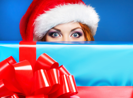 Young and beautiful girl with the Christmas present over blue backgroundの写真素材