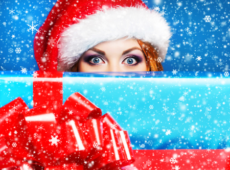 Teenager girl with a big Christmas present over winter background with a snowflakesの写真素材