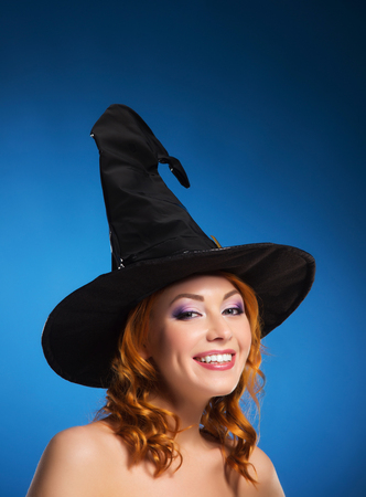 Portrait of young and beautiful witch over blue backgroundの写真素材