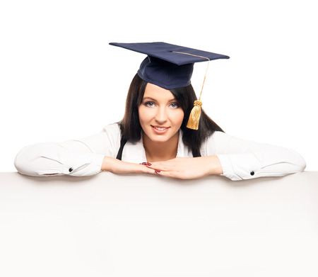 Young, beautiful and happy graduate girl with a blank banner isolated on whiteの写真素材