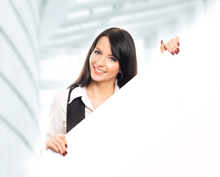 Young, confident, successful and beautiful business woman with a blank billboard over office backgroundの写真素材