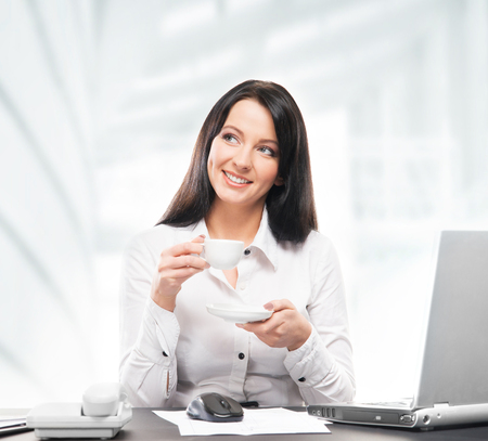 Young and attractive business woman drinking morning coffee in officeの写真素材