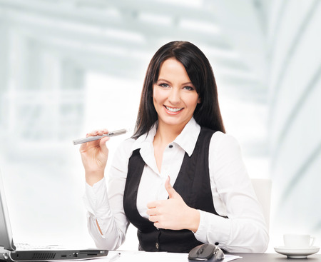 Young and attractive business woman with an electronic cigarette working in officeの写真素材