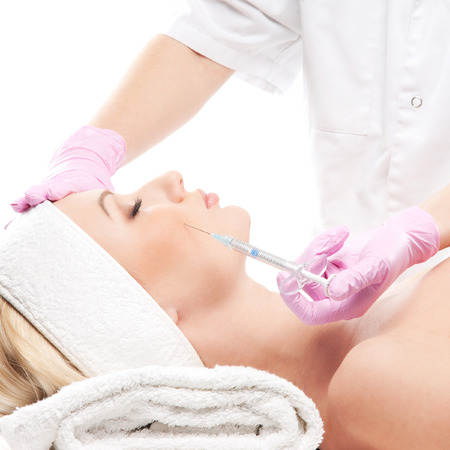 Beautiful woman gets an injection in her face isolated on whiteの写真素材