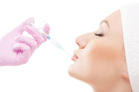 Beautiful woman gets an injection in her face isolated on whiteの写真素材