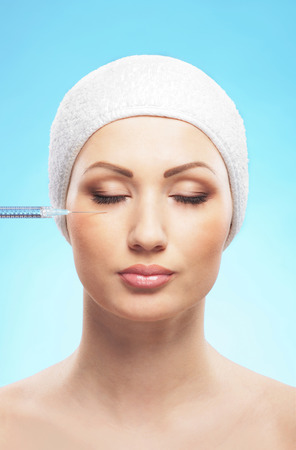 Beautiful woman gets an injection in her face isolated on whiteの写真素材