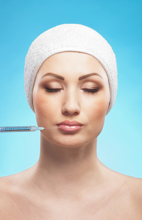 Beautiful woman gets an injection in her face isolated on whiteの写真素材