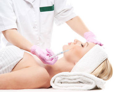 Beautiful woman gets an injection in her face isolated on whiteの写真素材