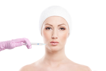 Beautiful woman gets an injection in her face isolated on whiteの写真素材