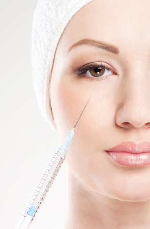 Beautiful woman gets an injection in her face isolated on whiteの写真素材