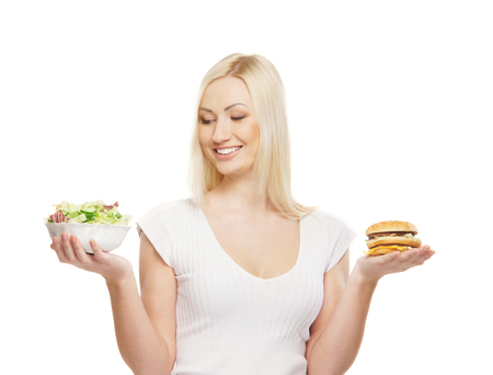 Young attractive girl making choice between healthy and harmful foodの写真素材