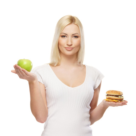 Young attractive girl making choice between healthy and harmful foodの写真素材
