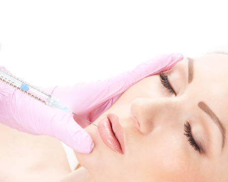 Beautiful woman gets an injection in her face isolated on whiteの写真素材