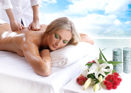 Young attractive sexy blond getting massage treatment isolated over white backgroundの写真素材