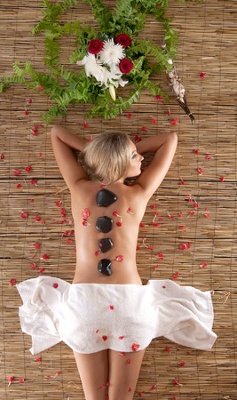 Attractive woman getting spa treatment laying on the bamboo matの写真素材